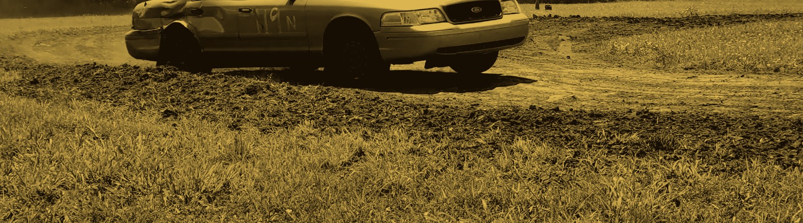 A Ford Crown Victoria sliding through a dirt RallyCross course